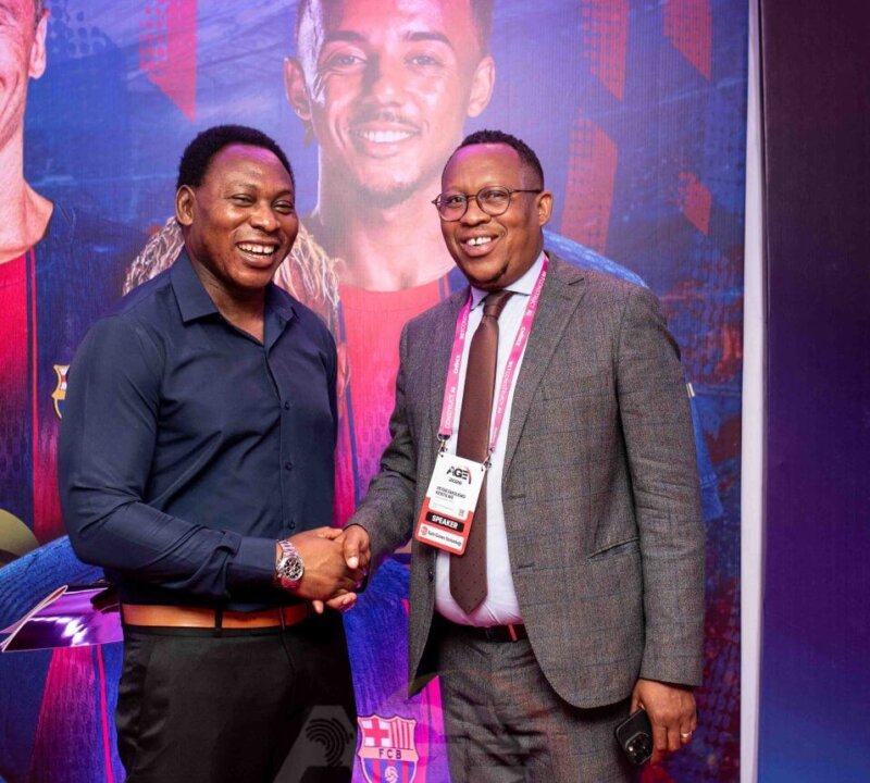 Two delegates shaking hands at the iGaming AFRIKA conference, one wearing a speaker badge