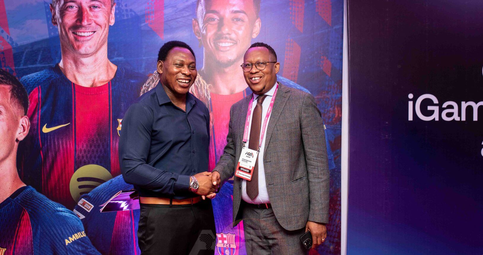 Two delegates shaking hands at the iGaming AFRIKA conference, one wearing a speaker badge